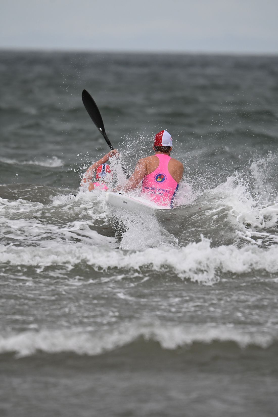 Závodník na surf ski pádluje přes vlnu